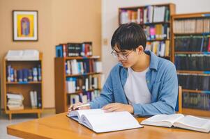 Male college students are working on laptops and searching for books to study, make reports, find useful information in college room. Concept of reading, learning and intelligence. photo
