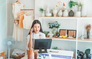 Small business owner talking on the phone with customers in a small shop. and check orders, check the orders that customers order from online retailers - online shopping photo