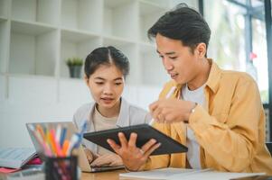 young university students consulting doing homework, cooperating research plan Discuss concepts and strategies. Prepare presentations on laptops and tablet computers. photo