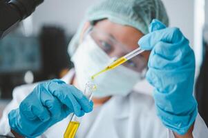 Female researchers are experimenting with pipette dropping a sample into a test tube in an experiment research in laboratory.. photo