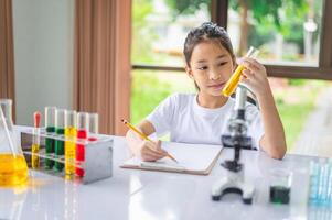 little scientist looking through a microscope and test tubes filled with chemicals for learning about science and experiments. photo