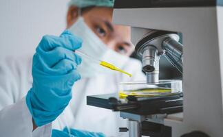 Female researchers are experimenting with pipette dropping a sample into a test tube in an experiment research in laboratory.. photo
