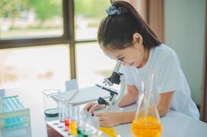 little scientist looking through a microscope and test tubes filled with chemicals for learning about science and experiments. photo