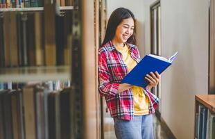 Students are reading and looking for books to study, make reports, find useful information on the bookshelves in the library. Concept of reading, learning and intelligence. photo