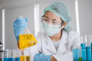 Female researchers are experimenting with pipette dropping a sample into a test tube in an experiment research in laboratory.. photo
