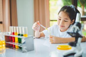 little scientist looking through a microscope and test tubes filled with chemicals for learning about science and experiments. photo
