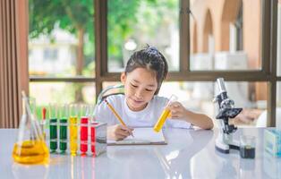 little scientist looking through a microscope and test tubes filled with chemicals for learning about science and experiments. photo