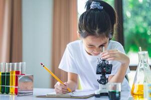 little scientist looking through a microscope and test tubes filled with chemicals for learning about science and experiments. photo