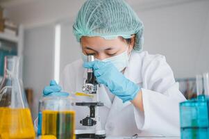 Female researchers are experimenting with pipette dropping a sample into a test tube in an experiment research in laboratory.. photo