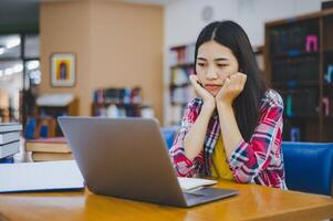 Students feel bored and stressed after working on their laptops and looking for books to study, make reports, find useful information in the university room. photo