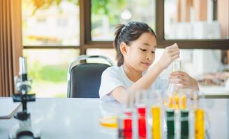 little scientist looking through a microscope and test tubes filled with chemicals for learning about science and experiments. photo
