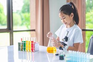 little scientist looking through a microscope and test tubes filled with chemicals for learning about science and experiments. photo
