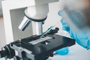 Female researchers are experimenting with pipette dropping a sample into a test tube in an experiment research in laboratory.. photo