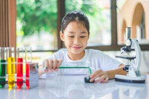 little scientist looking through a microscope and test tubes filled with chemicals for learning about science and experiments. photo