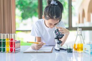 little scientist looking through a microscope and test tubes filled with chemicals for learning about science and experiments. photo