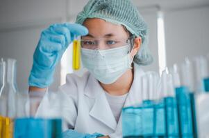 Female researchers are experimenting with pipette dropping a sample into a test tube in an experiment research in laboratory.. photo