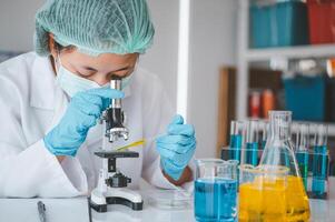 Female researchers are experimenting with pipette dropping a sample into a test tube in an experiment research in laboratory.. photo