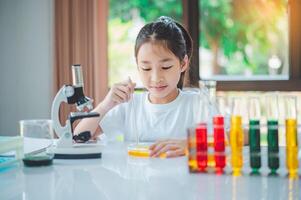little scientist looking through a microscope and test tubes filled with chemicals for learning about science and experiments. photo