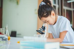 little scientist looking through a microscope and test tubes filled with chemicals for learning about science and experiments. photo
