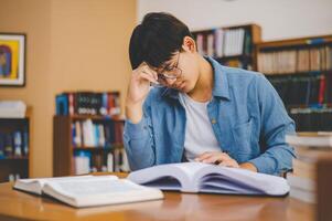 Students feel tired and stressed after working on their laptops and looking for books to study, make reports, find useful information in the university room. photo