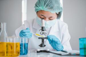 Female researchers are experimenting with pipette dropping a sample into a test tube in an experiment research in laboratory.. photo