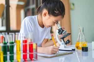 little scientist looking through a microscope and test tubes filled with chemicals for learning about science and experiments. photo