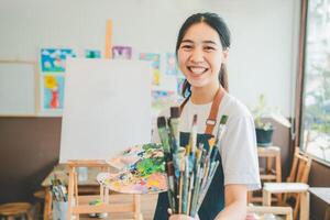 Portrait of Art student smiling happily while with watercolor painting on canvas doing some art projects on studio workshop photo
