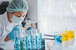 Female researchers are experimenting with pipette dropping a sample into a test tube in an experiment research in laboratory.. photo