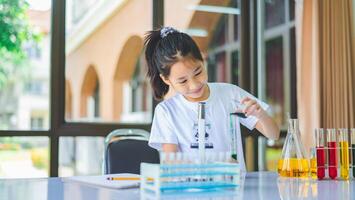little scientist looking through a microscope and test tubes filled with chemicals for learning about science and experiments. photo