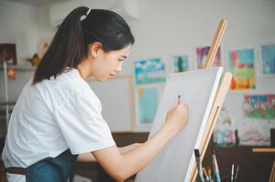Art student drawing with watercolor painting on canvas doing some art projects on studio workshop photo