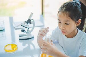 little scientist looking through a microscope and test tubes filled with chemicals for learning about science and experiments. photo