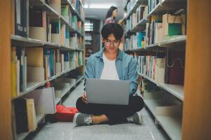 Male college students are working on laptops and searching for books to study, make reports, find useful information in college room. Concept of reading, learning and intelligence. photo