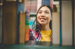 Female college students looking for books to study, make reports, find useful information on bookshelves in the library. Concept of reading, learning and intelligence. photo