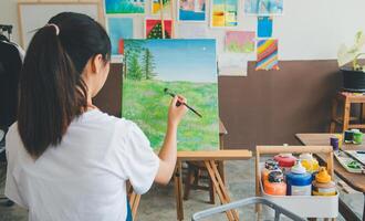 Art student drawing with watercolor painting on canvas doing some art projects on studio workshop photo