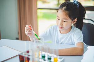 little scientist looking through a microscope and test tubes filled with chemicals for learning about science and experiments. photo