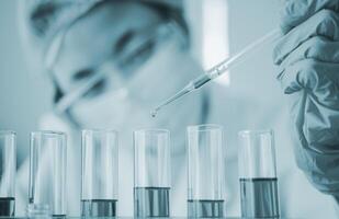 Female researchers are experimenting with pipette dropping a sample into a test tube in an experiment research in laboratory.. photo