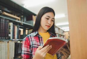 Students are reading and looking for books to study, make reports, find useful information on the bookshelves in the library. Concept of reading, learning and intelligence. photo