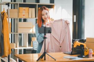 SME owner using the smartphone and tablet for recording . vlog and live stream at her shop,SME business concept, online shopping. photo