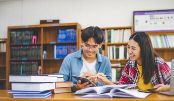 Students are consulting each other working on laptops and searching for books to study, make reports, find useful information in university room. Concept of reading, learning and intelligence. photo