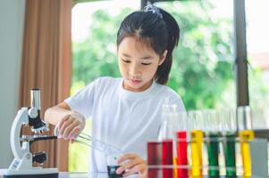 little scientist looking through a microscope and test tubes filled with chemicals for learning about science and experiments. photo