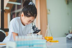 little scientist looking through a microscope and test tubes filled with chemicals for learning about science and experiments. photo