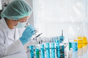 Female researchers are experimenting with pipette dropping a sample into a test tube in an experiment research in laboratory.. photo