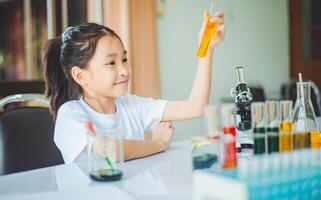 little scientist looking through a microscope and test tubes filled with chemicals for learning about science and experiments. photo