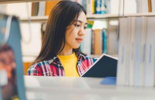 Students are reading and looking for books to study, make reports, find useful information on the bookshelves in the library. Concept of reading, learning and intelligence. photo