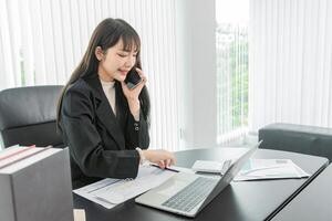 woman talking on the mobile phone and smiling while sitting at her working place in office. photo