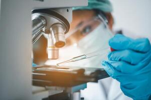 Female researchers are experimenting with pipette dropping a sample into a test tube in an experiment research in laboratory.. photo