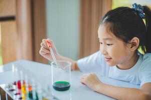 little scientist looking through a microscope and test tubes filled with chemicals for learning about science and experiments. photo
