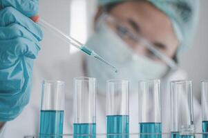 Female researchers are experimenting with pipette dropping a sample into a test tube in an experiment research in laboratory.. photo