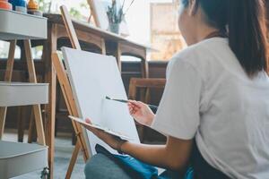Art student drawing with watercolor painting on canvas doing some art projects on studio workshop photo
