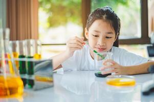 little scientist looking through a microscope and test tubes filled with chemicals for learning about science and experiments. photo